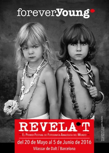 2016.png - Revela't 2026 Two young children wearing bead necklaces in a black-and-white promotional poster for the Reveal't photography festival, May 20–June 5, 2016, Vilassar de Dalt/Barcelona.