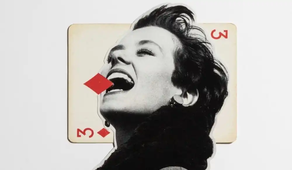 Black-and-white portrait of a man laughing, with a red 3 of diamonds playing card behind his mouth in a collage.