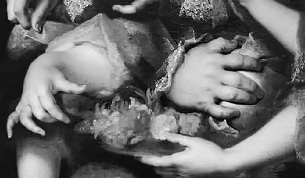 Close-up of multiple adults cradling a small child, with several hands supporting the baby from different sides in a protective embrace.
