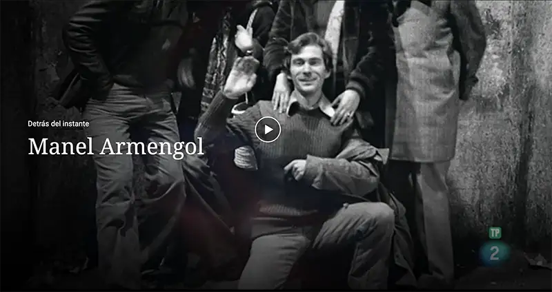 Video thumbnail: a smiling man seated among a group of people; play button centered, caption reads 'Detrás del instante Manel Armengol'.